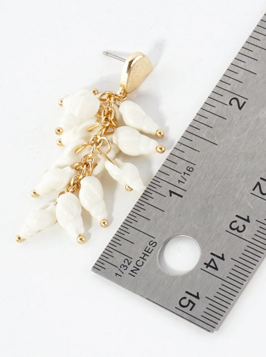 Earrings with gold and white beads next to a ruler for size reference